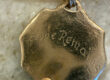 Gold pendant engraved “Hope Remains” with a small red stone.